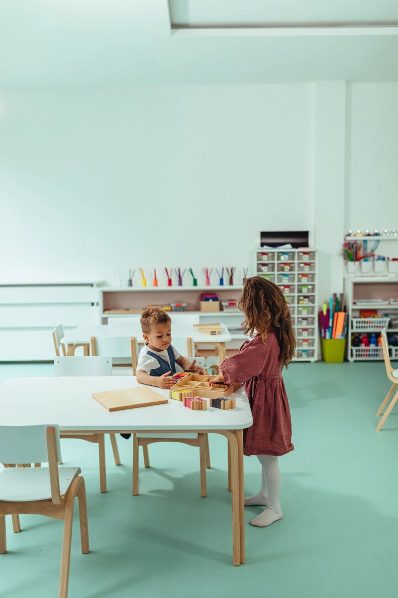 Boy and girl sitting at the table and playing with toys at kindergarten