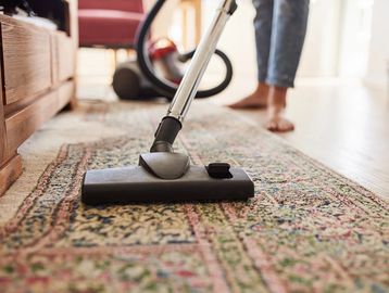 Vacuum cleaner cleaning a patterned rug.