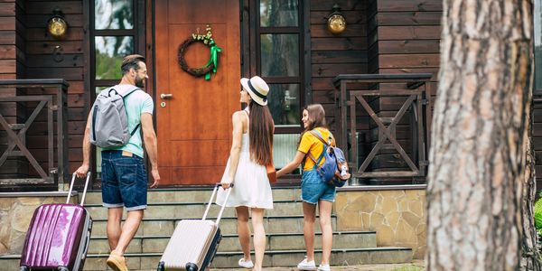 Family arriving with luggage at a cabin door.