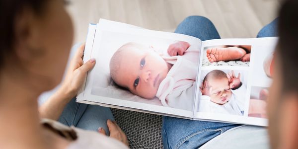 Fine Art Newborn Portrait Photographer Charleston SC parents look at album with baby photos 