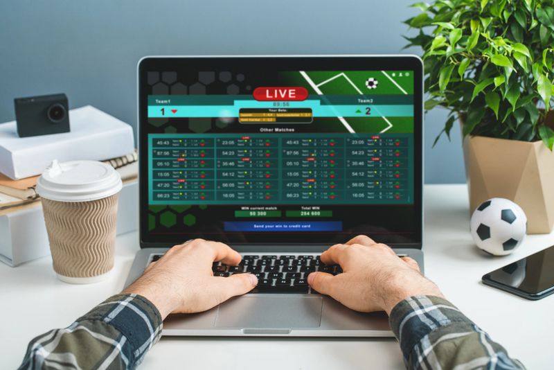 Front view of male hands typing on keyboard. Man using laptop for betting online at bookmaker's website. Sport, gambling, money win concept.