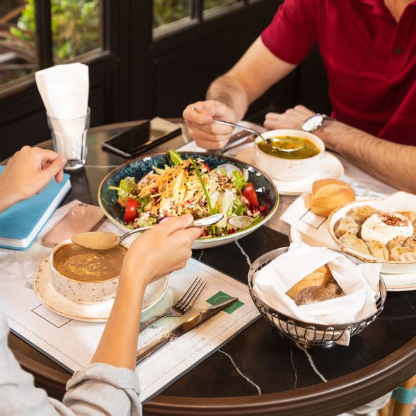 Two people enjoying a meal with soup, salad, and bread at a cozy table.