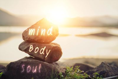 Stacked stones labeled mind, body, and soul at sunrise.