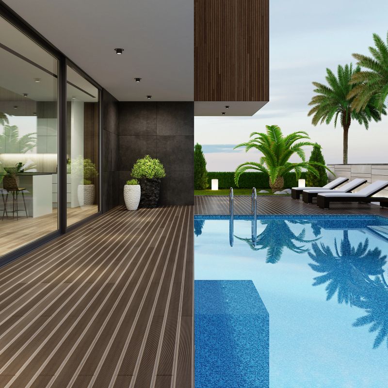 Luxurious villa with outside swimming pool at summer scene.Big blue swimming pool near living room and kitchen. Stylish and comfortable sun area with a modern brown sunbeds. Dark gray accent slate stone walls with natural plants.Natural floor tiles. Ceiling with white spotlights.+++ background is my photo.