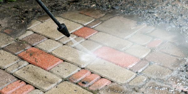 Pressure washing multicolored stone pavement.