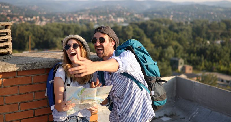 Happy young couple with a city map and a backpack travelling