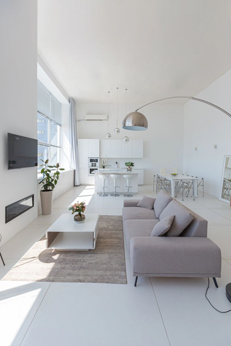 Cozy luxury modern interior design of a studio apartment in extra white colors with fashionable expensive furniture in a minimalist style. white tiled floor, kitchen, relaxation area and workplace.