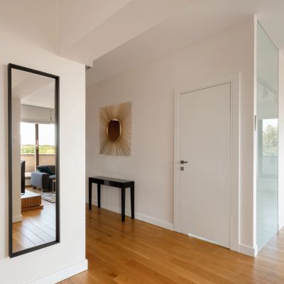 Minimalist hallway with wooden floor and mirror.
