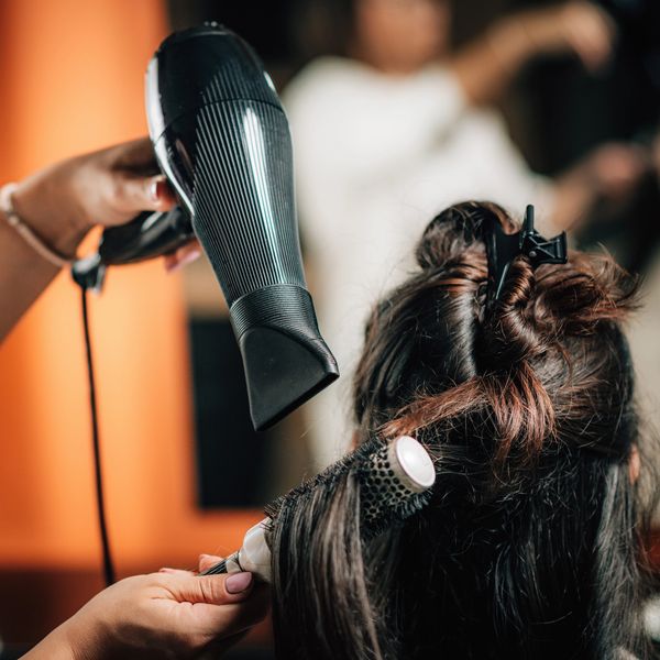 Close-up of hairstylist blow-drying hair with round brush.