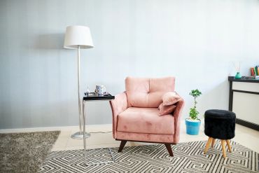 Cozy pink armchair with a side table and floor lamp in a modern living room.