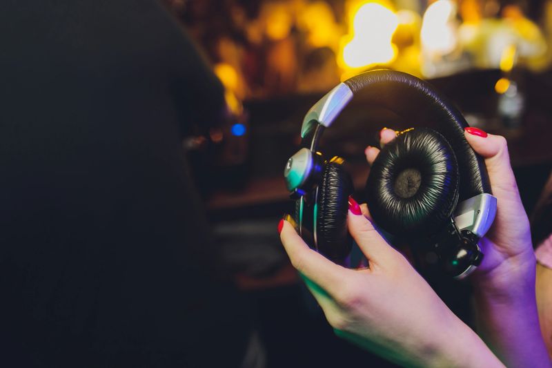 Female hands fold folding stereo headphones on a club background