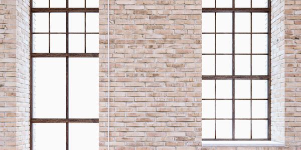 Two large arched windows in a brick wall with wooden floor.