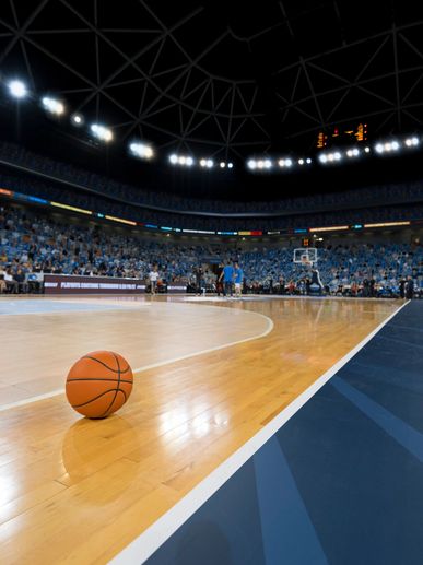 Basketball on court in a large indoor arena with audience.