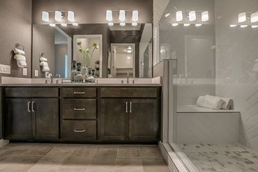 Modern bathroom with double vanity and glass shower enclosure.