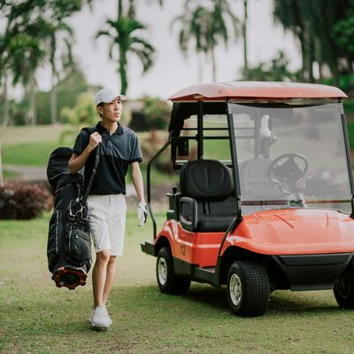 Man sitting in a golf cart on a grassy field.