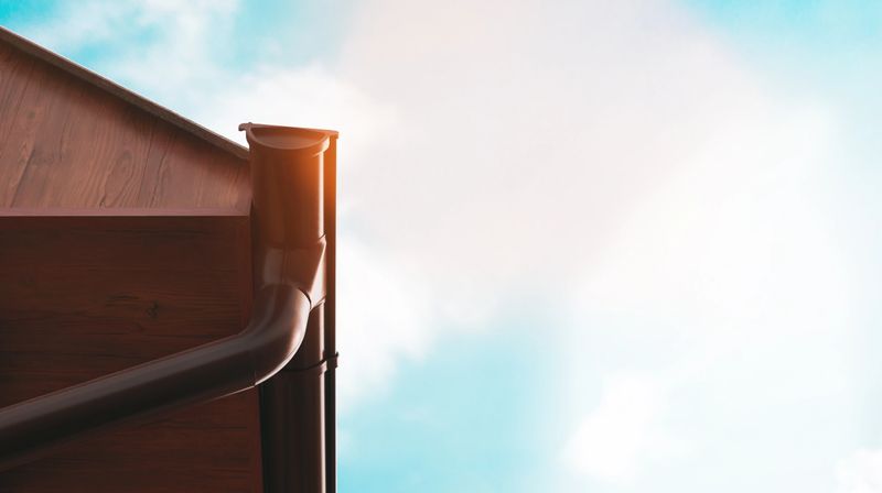 Close-up of newly installed seamless gutters reflecting sunlight on a residential home.