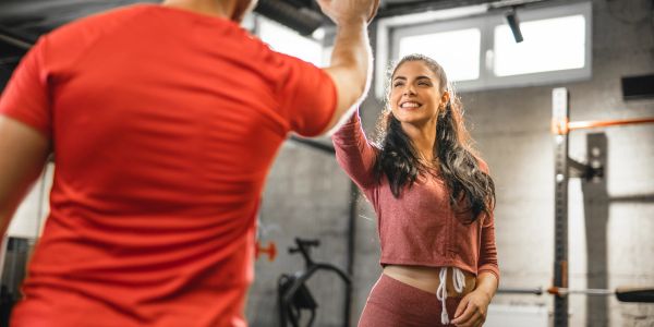 Two people giving a high-five in a gym.