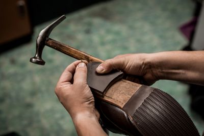 Hands fixing a shoe sole with a hammer.