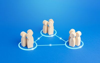 Wooden figures grouped in three connected circles on blue background.
