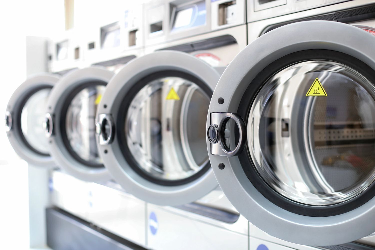 Row of modern front-loading washing machines in a laundromat.