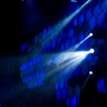 Blue stage lights casting beams in a dark setting.