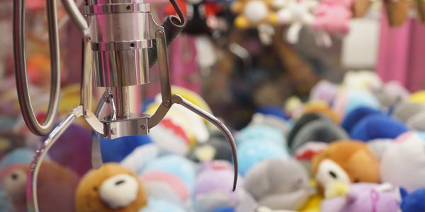 The Claw Zone Close-up of a claw machine grabbing plush toys in an arcade.