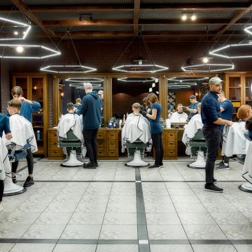 Barbería moderna con varios clientes y peluqueros.