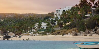 Beachfront houses with palm trees at sunset.
