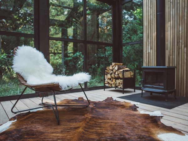 A cozy glass-walled cabin with a wood stove.