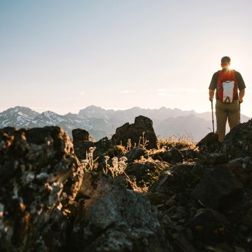 Persona de pie en un paisaje montañoso al amanecer.