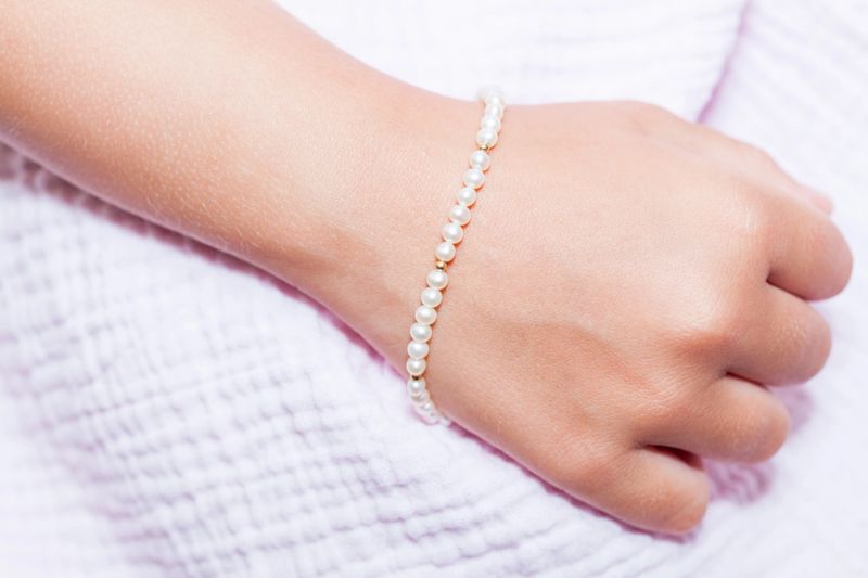 Arm with a pearl bracelet on a lavender dress