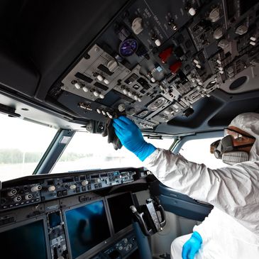 A person in protective gear cleaning an airplane cockpit.