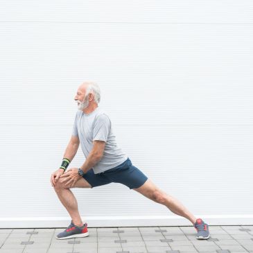 Senior man stretching leg outdoors.