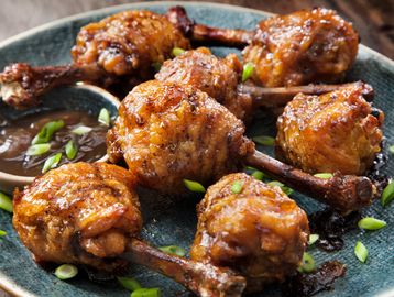 Crispy fried chicken drumettes garnished with green onions and dipping sauce.