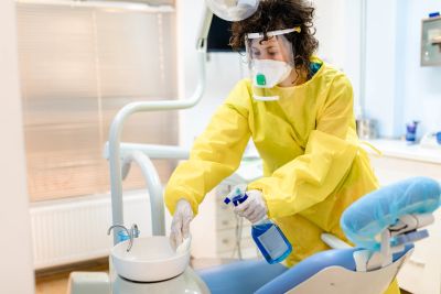 Healthcare worker disinfecting dental chair.