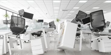 Modern office with chairs and desks in disarray, some furniture tipped over.