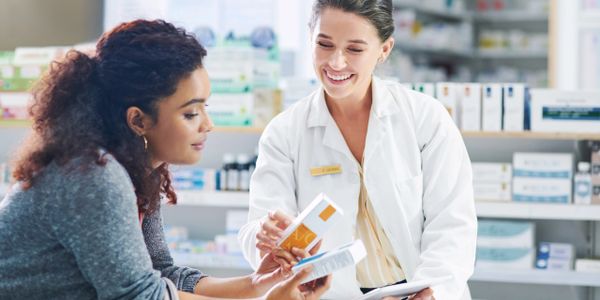 Pharmacist explaining medication to a customer in a pharmacy.