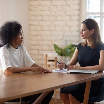 Two women engaged in a conversation at a wooden table.
