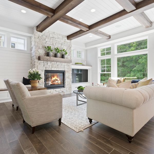 Bright living room with large windows, stone fireplace, and beige furniture.