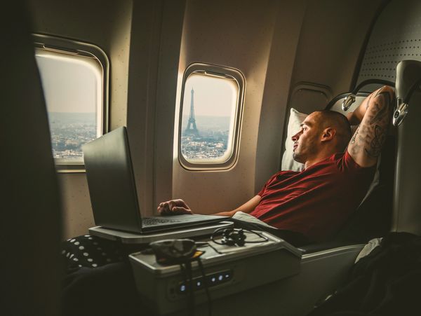 Man resting on airplane with Eiffel Tower view.