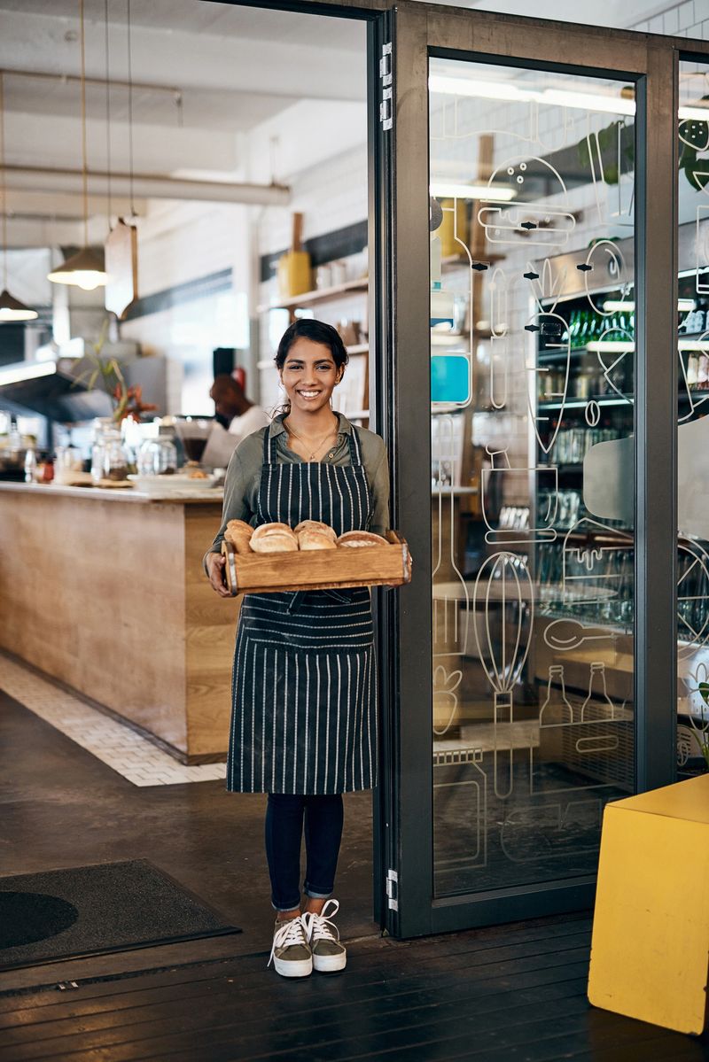 Shot of a young woman holding a selection of freshly baked breads in her bakery