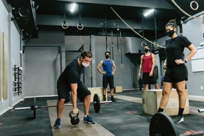 Personas entrenando con pesas y kettlebell en el gimnasio.