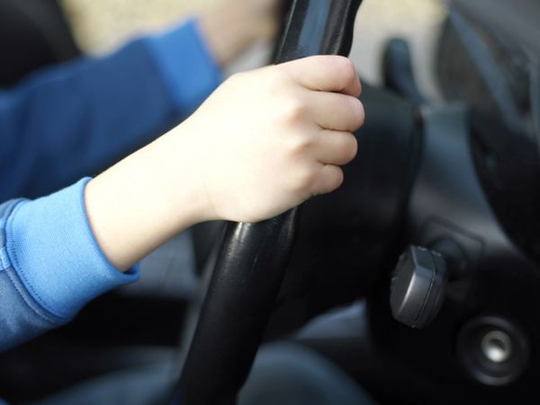 Hands gripping a car steering wheel while driving.