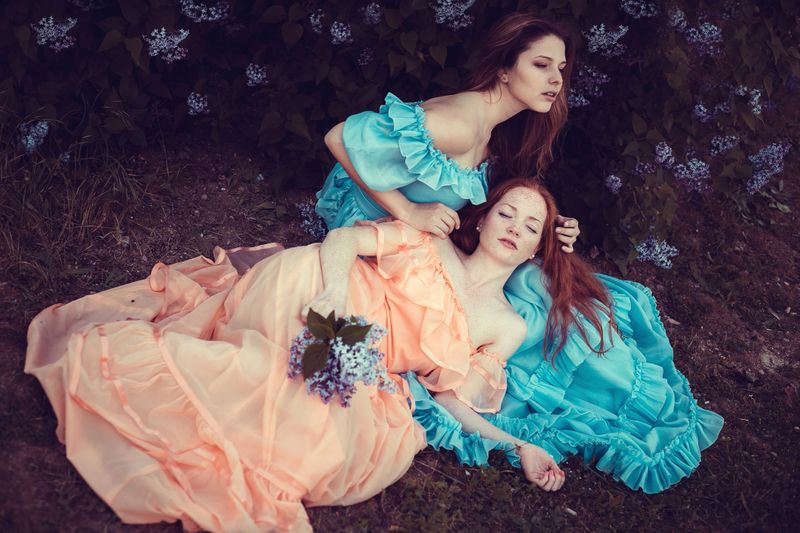 Beautiful women enjoying lilac garden, young women with flowers in green park. cheerful teenagers walking outdoor. soft light style color