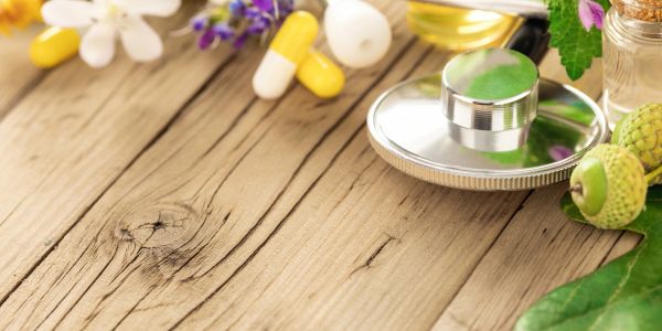 Stethoscope, capsules, and natural herbs on a wooden surface.