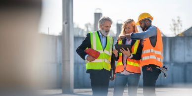 Three engineers discussing plans on a construction site.