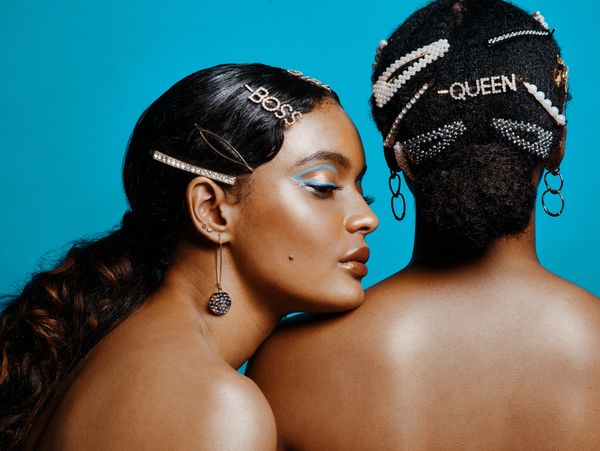Two women with stylish hairpins labeled 'BOSS' and 'QUEEN' against a blue background.