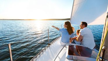 Family enjoying a peaceful sail on the water at sunset.
