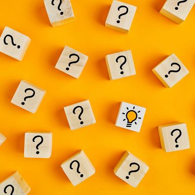 Wooden blocks with question marks and one with a light bulb on orange background.