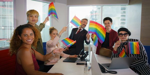 Diverse group celebrating LGBTQ+ pride in an office.
